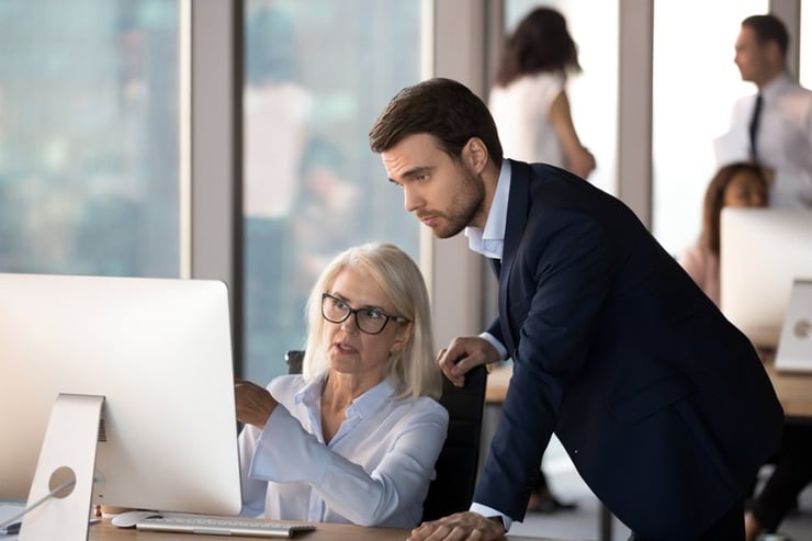 Young employee helps middle aged colleague learn corporate program-2