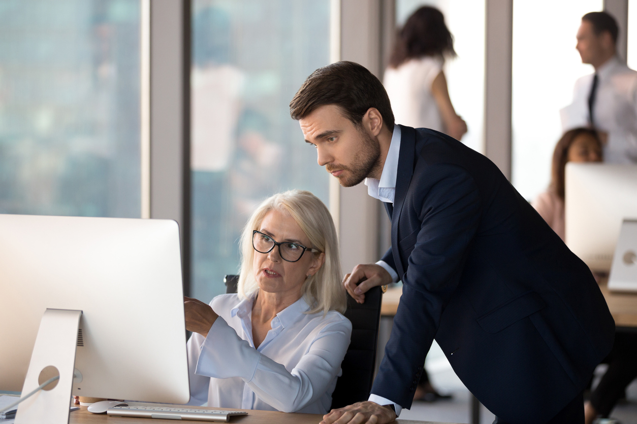 Young employee helps middle aged colleague learn corporate program